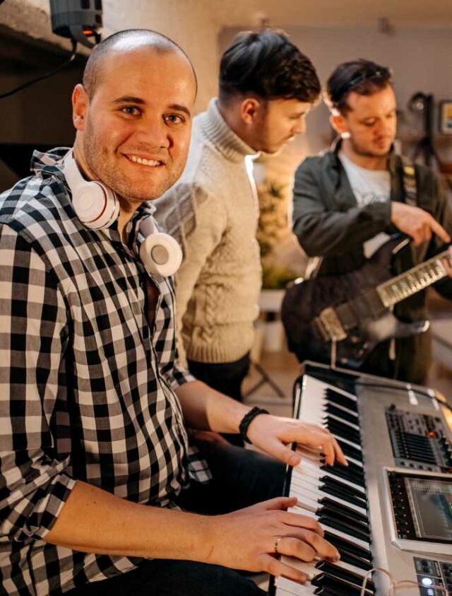 Tecladista tocando em grupo e sorrindo